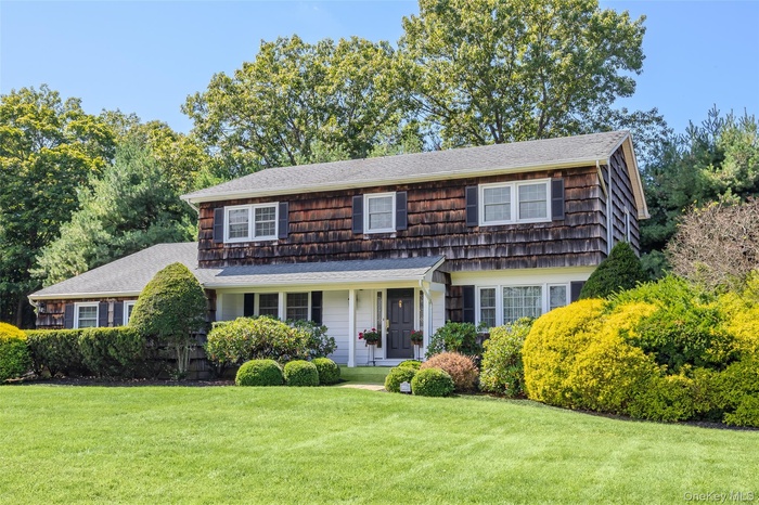 View of front of house featuring a porch, a shingled roof, and a front yard