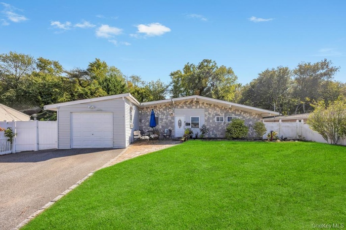 View of front of home featuring driveway, stone siding, and a garage