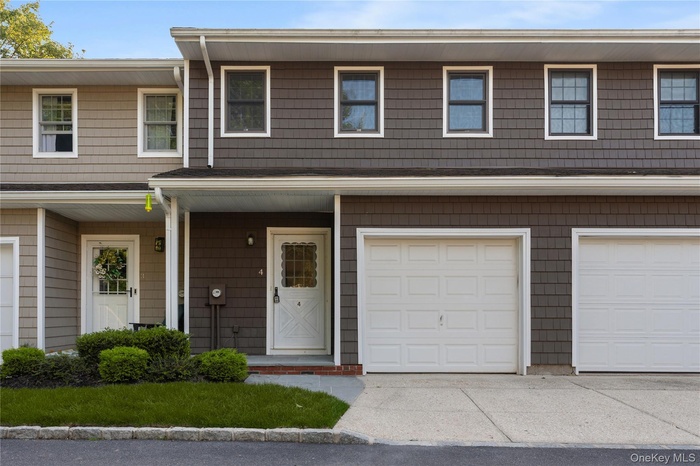Traditional-style home with covered porch, a garage, and driveway
