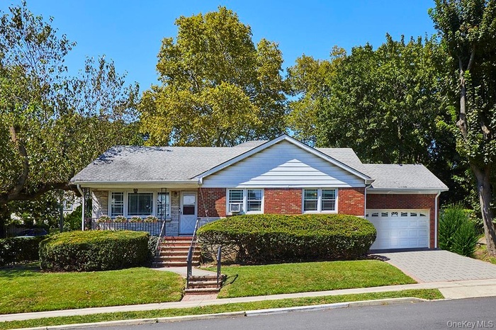 Single story home with a front lawn, a garage, decorative driveway, and a shingled roof