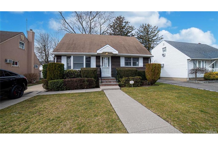 View of front of property featuring a front yard and roof with shingles