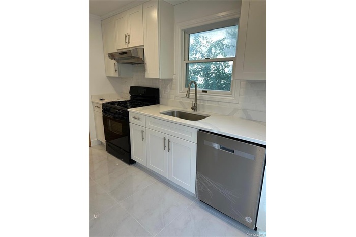 Kitchen featuring black range with gas cooktop, decorative backsplash, stainless steel dishwasher, and white cabinetry