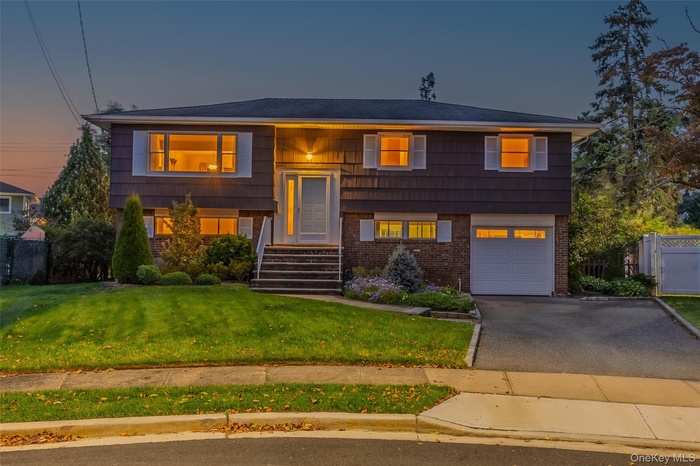 Bi-level home with brick siding, driveway, and an attached garage