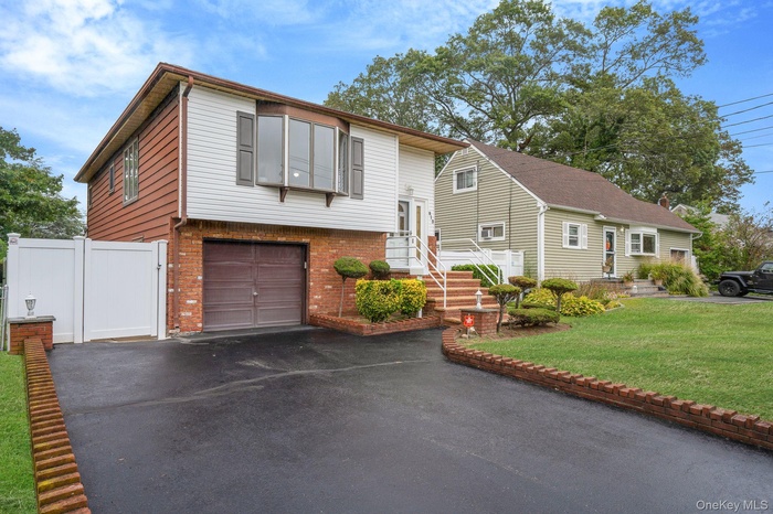 Split foyer home featuring brick siding, asphalt driveway, and a garage
