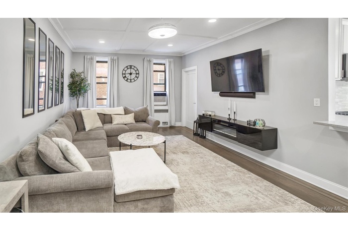 Living room with dark wood-type flooring, crown molding, and recessed lighting