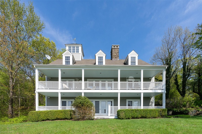 Back of property featuring a balcony, a chimney, a lawn, and french doors