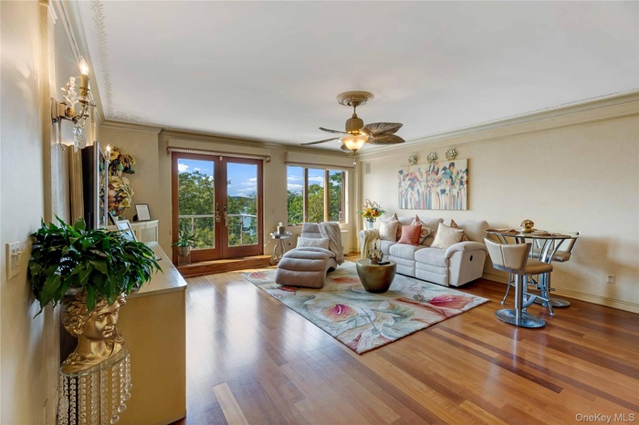 Living room with wood finished floors, crown molding, a ceiling fan, and french doors