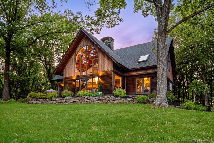 View of front of home featuring a shingled roof, a yard, and a chimney