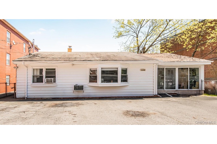 Rear view of house featuring cooling unit, roof with shingles, and fence