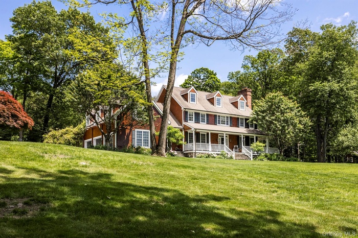 View of front of house featuring covered porch, a front yard, and a chimney