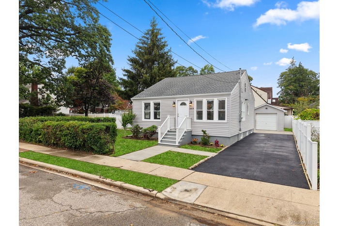 Bungalow featuring a shingled roof, an outdoor structure, a detached garage, and asphalt driveway
