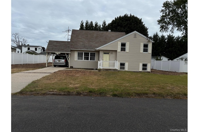 Split level home with concrete driveway, a carport, and a shingled roof
