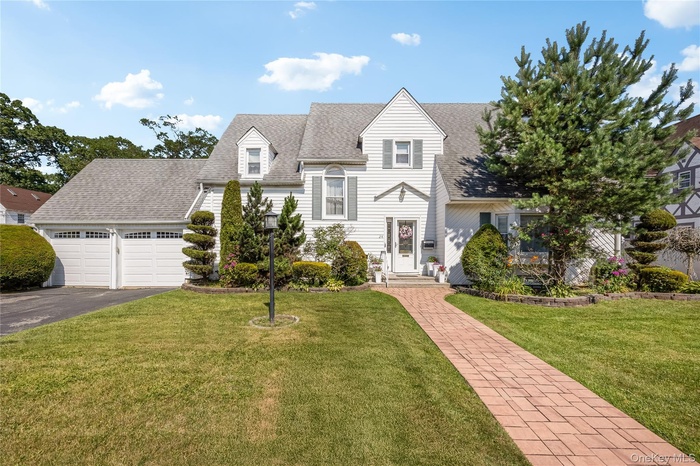 View of front of home featuring roof with shingles, driveway, an attached garage, and a front yard