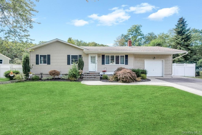 Single story home with an attached garage, a chimney, asphalt driveway, and entry steps