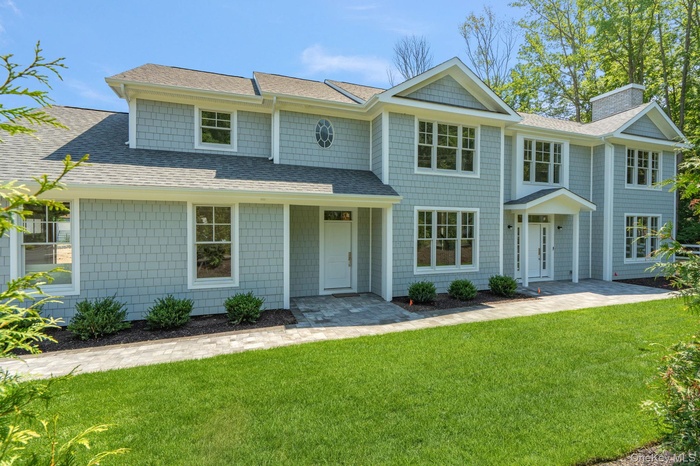 Shingle-style home featuring roof with shingles, a front yard, and a chimney
