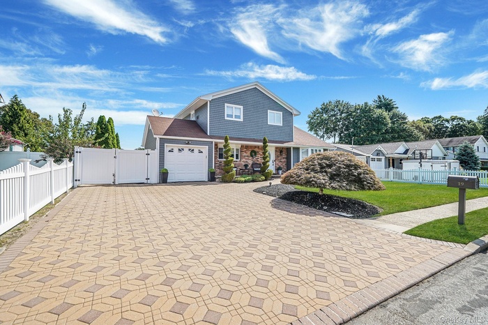 Traditional home with a gate, decorative driveway, and an attached garage