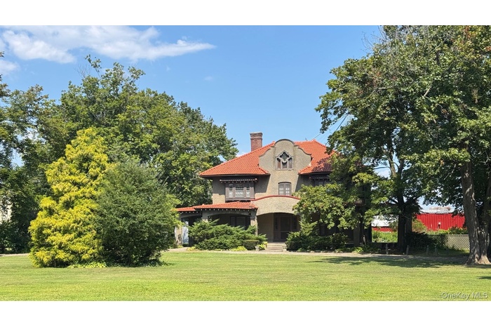 Mediterranean / Spanish-style home with a chimney, a front yard, stucco siding, and a clay tile roof.