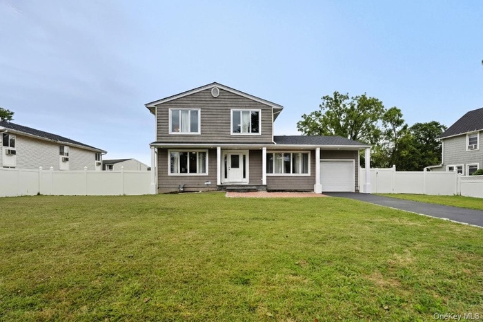 Traditional-style home featuring asphalt driveway, a garage, and a porch