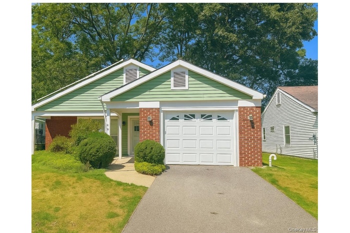 View of front of property with brick siding, driveway, a front yard, and a garage