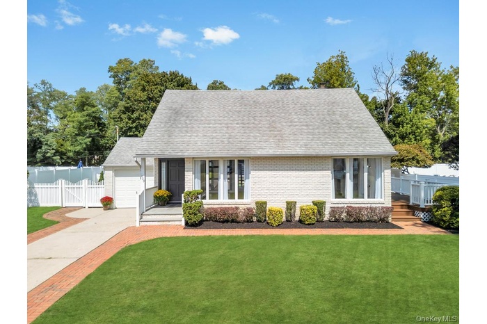 View of front facade featuring roof with shingles, brick siding, driveway, and a garage