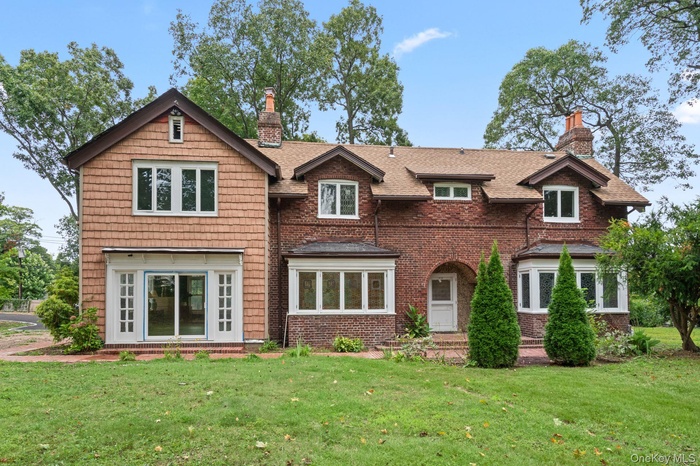 View of front facade featuring a chimney, brick siding, and a front yard
