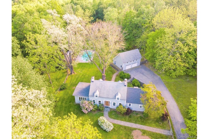 Aerial view of property and surrounding area with a forest