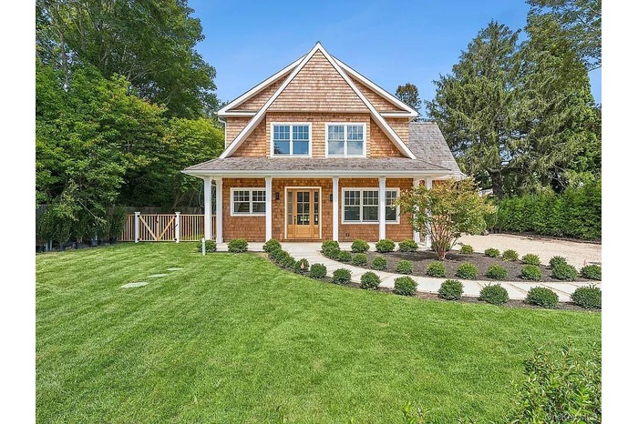 Shingle-style home with covered porch and roof with shingles