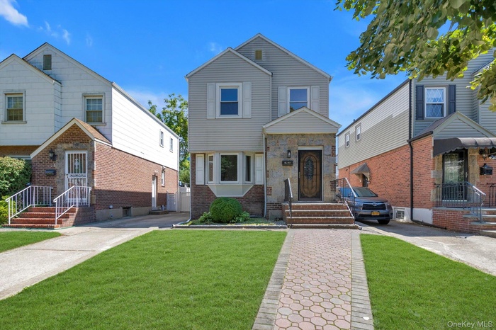 View of front of property with a front lawn, driveway, and brick siding