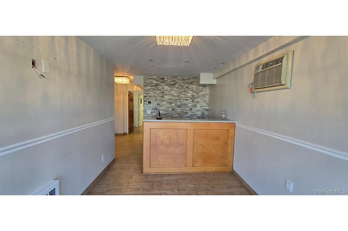 Kitchen with wood finished floors, an AC wall unit, and light countertops