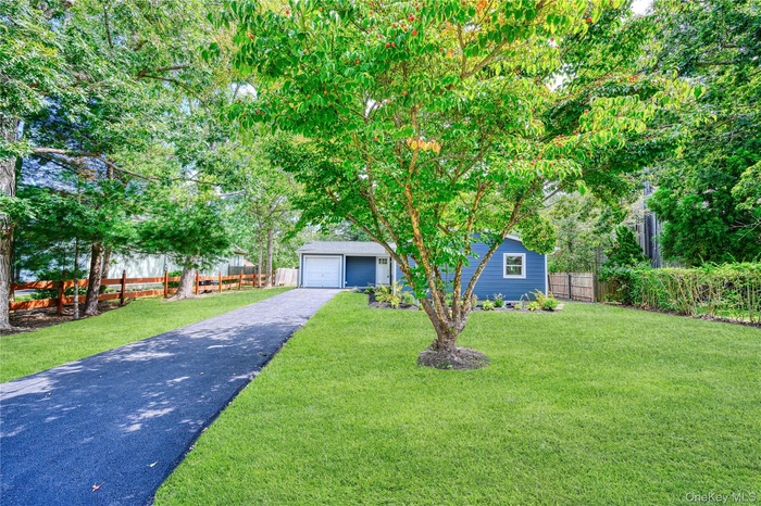 View of property hidden behind natural elements with an outbuilding and a detached garage