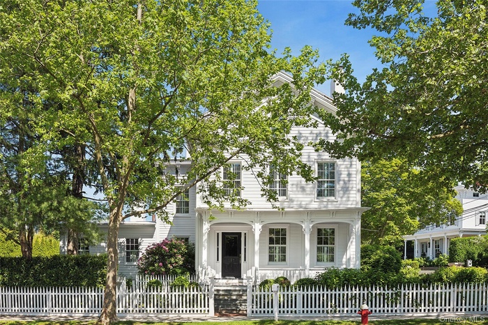 View of front of house with covered porch, a fenced front yard, and a gate