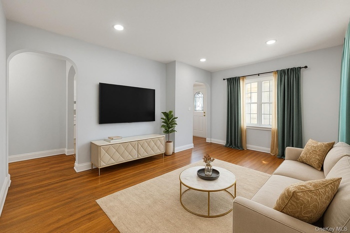 first floor Living area featuring arched walkways, wood finished floors, and recessed lighting (Virtually staged)