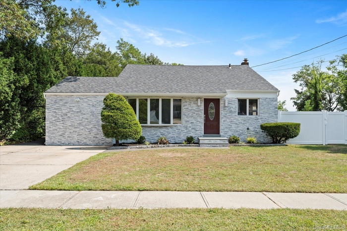 View of front of house with roof with shingles, a chimney, and stone siding