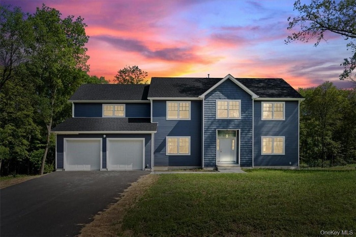 View of front facade with a lawn and a garage