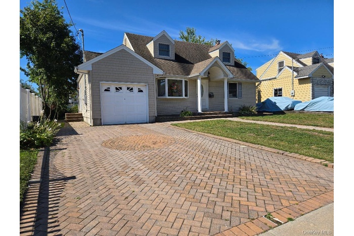 Cape cod home featuring decorative driveway, an attached garage, and roof with shingles