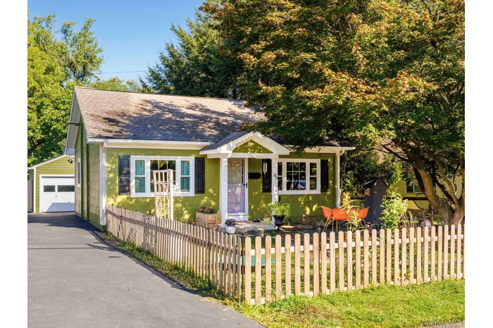 Bungalow with a shingled roof, an outbuilding, a garage, and a fenced front yard
