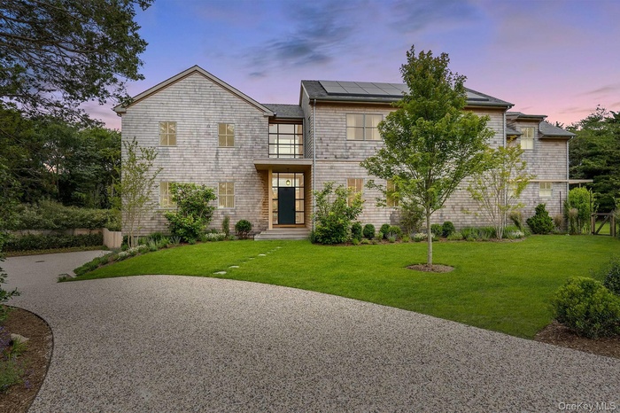 View of front of house featuring a lawn, roof mounted solar panels, and driveway