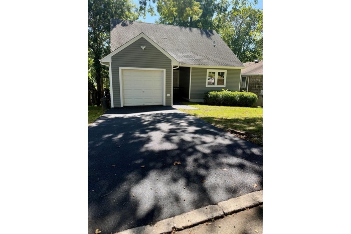 View of front facade with a shingled roof, asphalt driveway, a garage, and a front yard