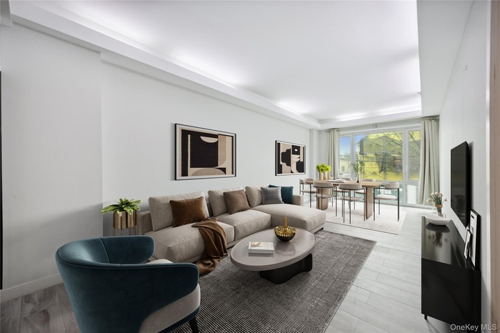 Living area featuring a raised ceiling, light wood-type flooring, and baseboards