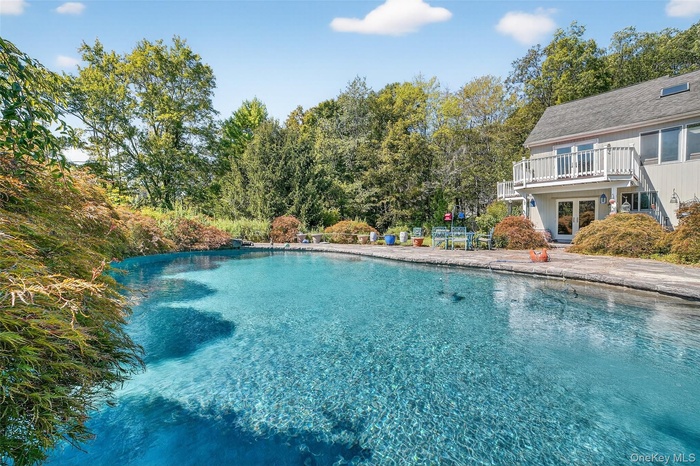 Swimming pool with a patio and view of wooded area