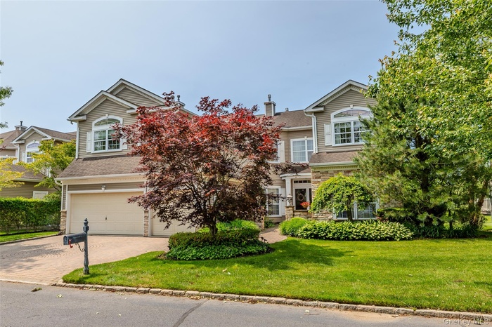 View of front facade with an attached garage, decorative driveway, and a front lawn