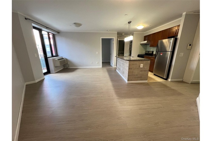 Kitchen featuring freestanding refrigerator, hanging light fixtures, light wood-style floors, dark stone countertops, and gas range