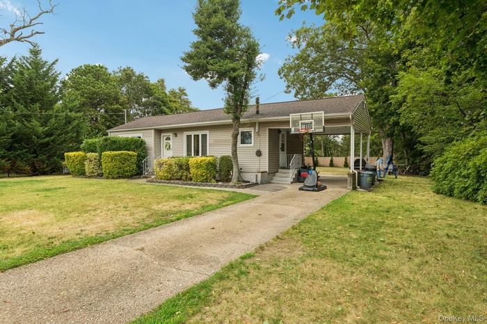 View of front facade featuring a front yard, an attached carport, and concrete driveway