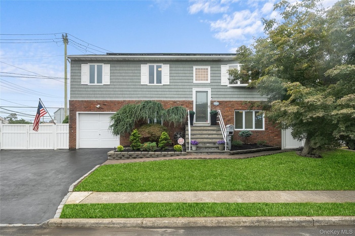 Split foyer home featuring asphalt driveway, a garage, and brick siding