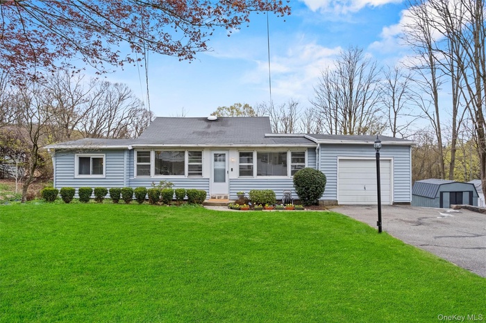 View of front of house featuring asphalt driveway, a garage, a front yard, and roof with shingles