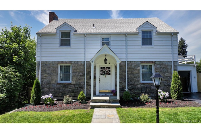 View of front of house with stone siding, a chimney, and roof with shingles