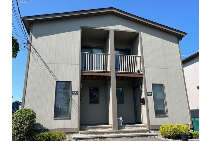 View of front of property featuring covered porch and a balcony