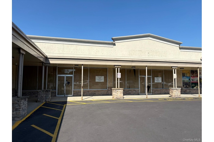 View of exterior entry with stone siding and uncovered parking