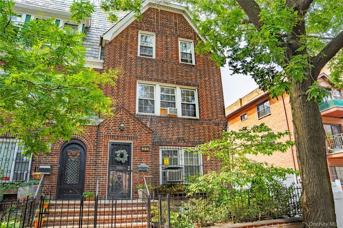 Tudor-style house featuring brick siding and a fenced front yard