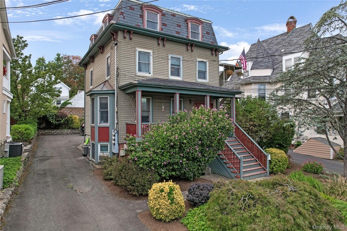 Victorian home with a porch, mansard roof, and stairs